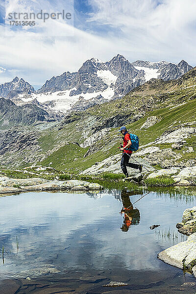 Mann geht am See entlang mit Spiegelung in den westlichen Rätischen Alpen Sondrio  Italien