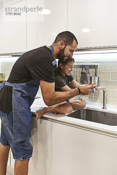 Vater und Tochter waschen sich zu Hause im Spülbecken die Hände
