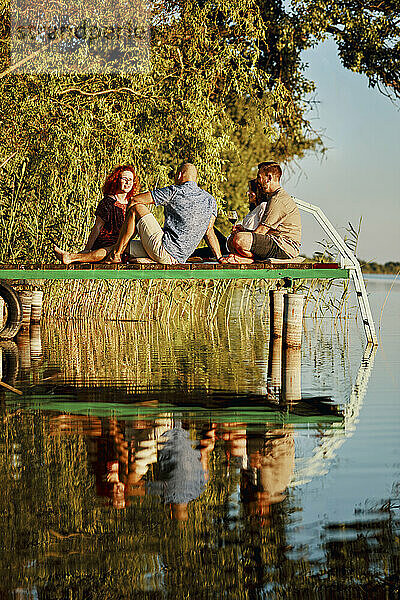 Freunde beim Picknick am Steg an einem See