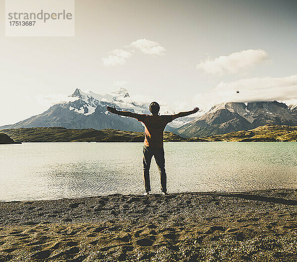Mann steht mit ausgestreckten Armen am Pehoe-See im Torres-Del-Paine-Nationalpark in Patagonien  Südamerika
