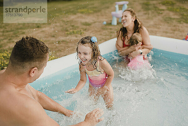 Glückliche Familie in einem aufblasbaren Swimmingpool im Garten