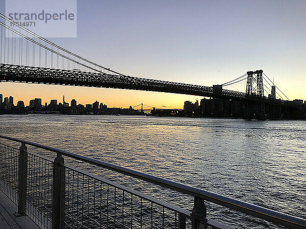Williamsburg Bridge und Blick auf den Fluss und die Skyline von Manhattan bei Sonnenuntergang