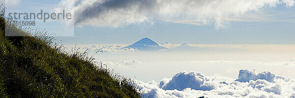 Panorama-Landschaftsfoto des Mount Agung  des höchsten Vulkans auf Bali  der sich hoch über den Wolken erhebt  vom Campingplatz aus am ersten Tag des dreitägigen Mount Rinjani Trek  Lombok  Indonesien  Asien  Hintergrund mit Kopierraum