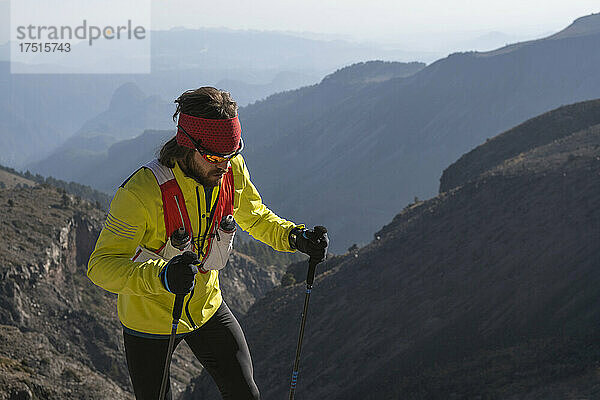 Ein Mann in Gelb wandert mit Stöcken zum Pico de Orizaba hinauf