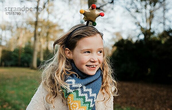 Lächelndes Mädchen mit einem Weihnachtsstern-Stirnband  das draußen spielt