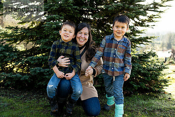Glückliche Mutter mit Jungen vor dem Weihnachtsbaum auf dem Bauernhof