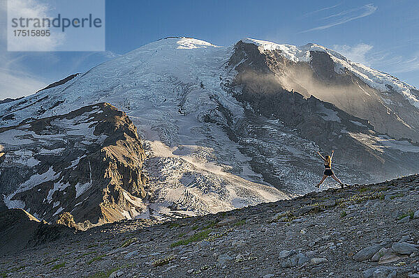 Fitte Frau springt voller Spannung auf einem Bergrücken neben dem Mount Rainier