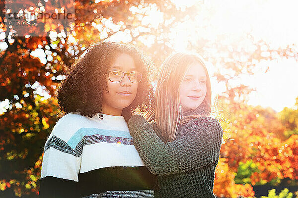Zwei hübsche Tween-Mädchen im Hintergrund in Herbstfarben beleuchtet.