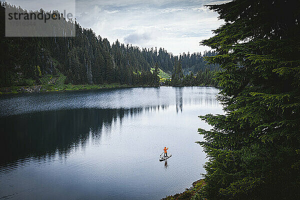 Eine Frau steht auf einem Paddelbrett am Bergsee