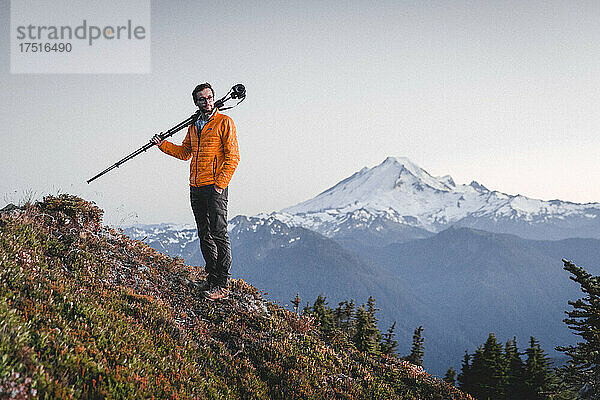 Ein Mann mit einer Kamera steht in North Cascades in der Nähe des Berges. Bäcker