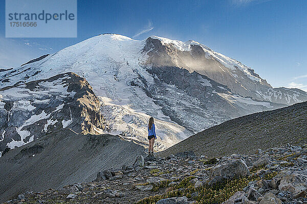 Frau im blauen Hemd steht vor dem Mount Rainier
