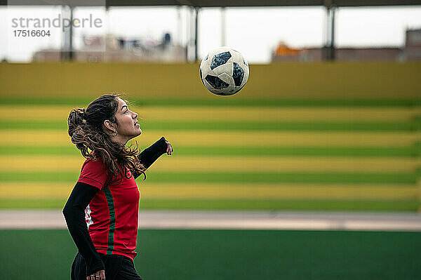 Junge Fußballspielerin kickt den Ball auf dem Spielfeld
