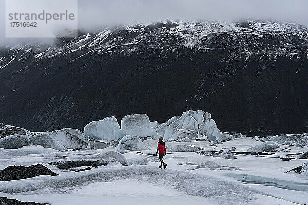 Frau in roter Jacke spaziert im Urlaub durch Gletscherlandschaft