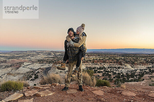 Glücklicher Mann huckepack  Frau in der Wüste bei Sonnenuntergang