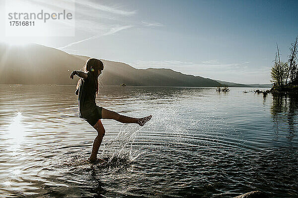 Junges Mädchen tritt und planscht im Wasser an einem See