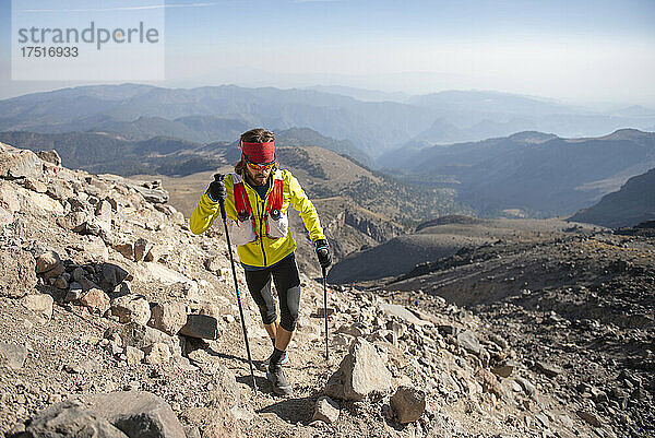 Ein Mann in Gelb klettert mit Stöcken zum Pico de Orizaba