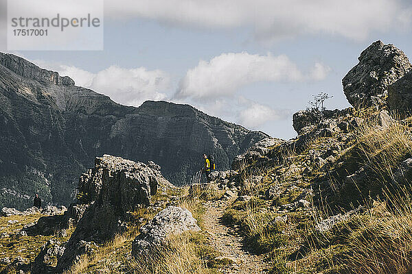 Ein glücklicher Mann in gelber Kleidung wandert im Rückblick in den Bergen.