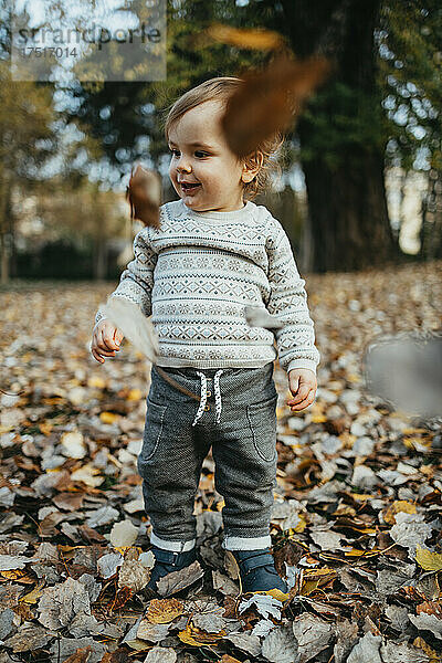 Entzückender einjähriger Junge  der im Herbstpark spaziert und spielt.
