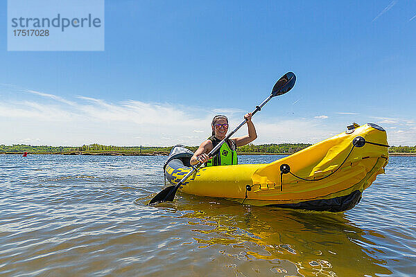 Lächelnde Frau im gelben Kajak auf dem Wasser in Neuengland