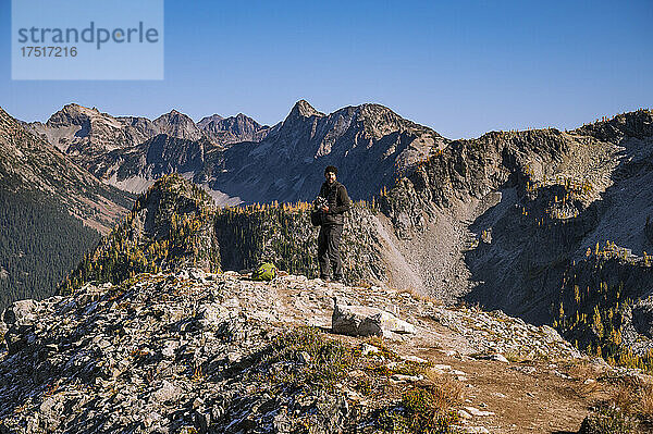 Fotograf hält Kamera auf einem Bergrücken
