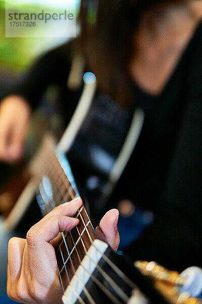 Junge Frau spielt Gitarre in der Natur