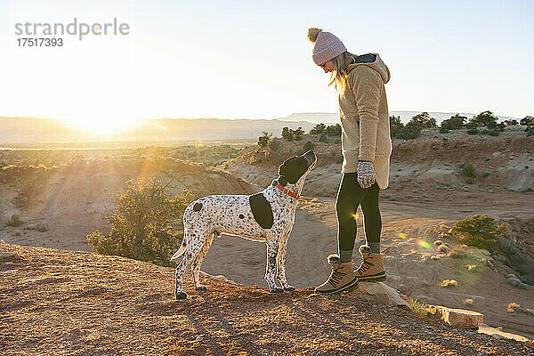 Wanderin schaut Hund an  während sie bei Sonnenuntergang in der Wüste steht