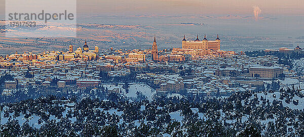 Verschneite Altstadt mit Burg auf einem Hügel mit goldenen Farben bei Sonnenuntergang