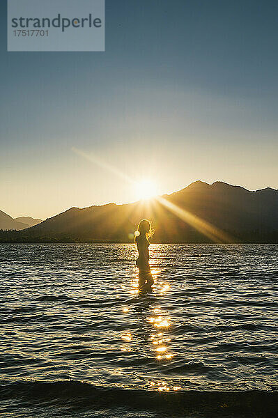 Frau schwimmt im Bikini bei Sonnenuntergang am Lake Wenatchee