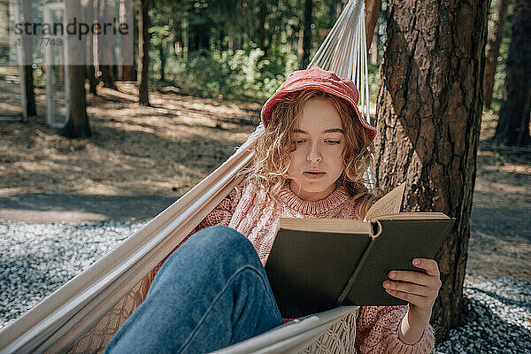 Frau in der Hängematte liest Buch im Wald  Nahaufnahme.