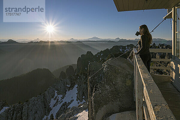 Frau trinkt Kaffee bei Sonnenaufgang am Feueraussichtspunkt Mount Pilchuck