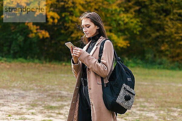 Junges brünettes Mädchen hält Smartphone in der Hand und checkt Nachrichten