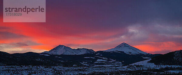 Idyllische Aufnahme einer Bergkette vor orangefarbenem Himmel bei Sonnenaufgang