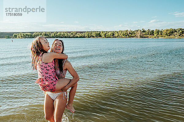 Schwestern spielen an einem sonnigen Tag im seichten See