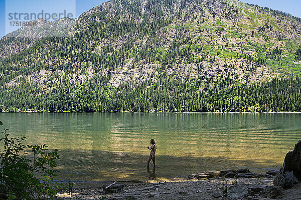 Mädchen im Bikini steht in einem See  umgeben von Bergen