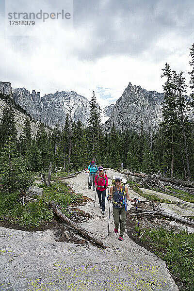 Female hikers smile on the trail in front of Lone Eagle Peak