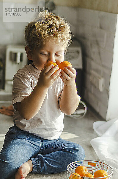 Kind schnuppert reife Mandarinen in seinen Händen