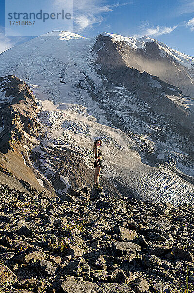 Fitte junge Frau  die auf einer Klippe neben dem Mount Rainier steht