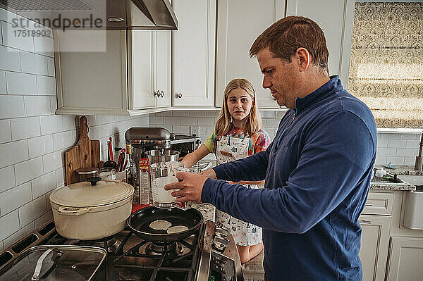 Vater und Tochter backen Pfannkuchen in der Küche
