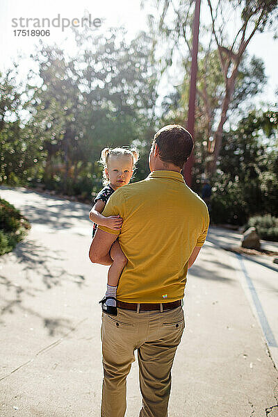 Vater trägt Kleinkindtochter im Garten in Kalifornien