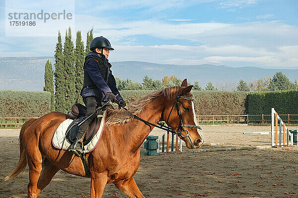 Kind reitet auf der Ranch mit Hindernissen und Barrieren.