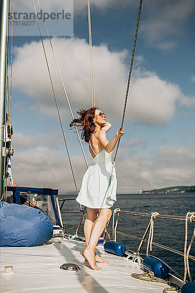 Frau steht auf dem Yachtdeck vor dem Himmelshintergrund
