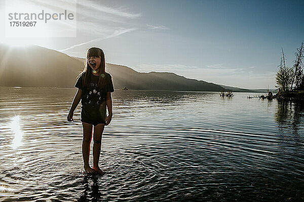 Glückliches junges Mädchen  das an einem sonnigen Tag im See spielt