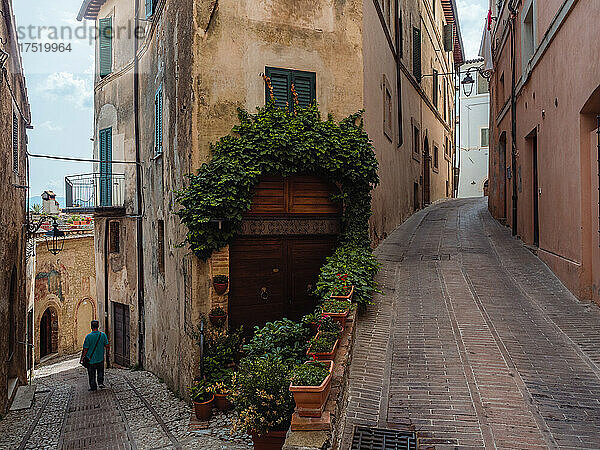 Eine Person  die an einer Gabelung durch die zentralen Straßen der Altstadt von Trevi geht  Trevi  Umbrien  Italien  Europa