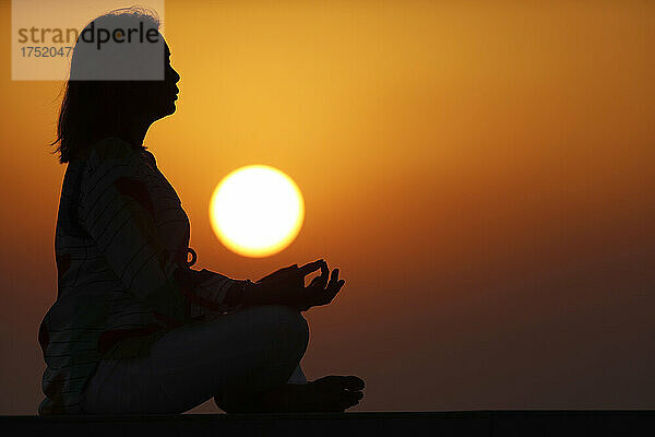 Frau praktiziert Yoga-Pose und Meditation bei Sonnenuntergang als Konzept für Stille und Entspannung  Vereinigte Arabische Emirate  Naher Osten