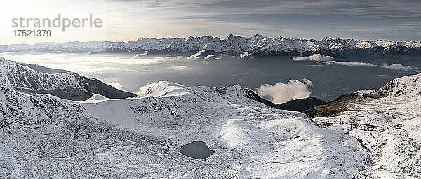 Luftaufnahme der schneebedeckten Orobie-Alpen und Piani di Rhön  die im Morgengrauen aus dem Herbstnebel auftauchen  Rätische Alpen  Lombardei  Italien  Europa