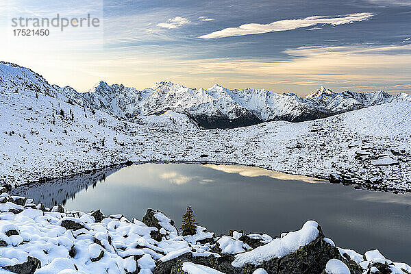 Mit Schnee bedeckte Berggipfel der Orobie-Alpen  die sich im Morgengrauen im gefrorenen Rogneda-See spiegeln  Rätische Alpen  Lombardei  Italien  Europa