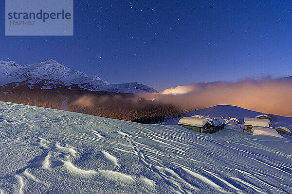 Mit Schnee bedeckte Berghütten unter dem sternenklaren Winterhimmel  Andossi  Madesimo  Valchiavenna  Valtellina  Lombardei  Italien  Europa