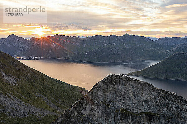 Menschen bewundern den Himmel im Morgengrauen und stehen auf einem Berggipfel über den Fjorden  Insel Senja  Kreis Troms  Norwegen  Skandinavien  Europa