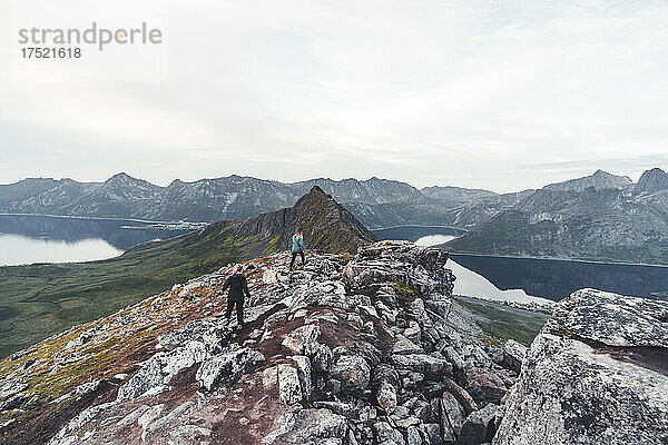 Zwei junge Wanderinnen erklimmen die Felsen am Hesten-Berggipfel  Senja  Kreis Troms  Norwegen  Skandinavien  Europa