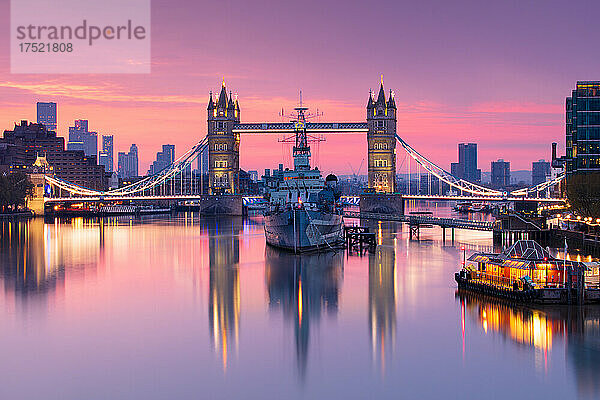 Sonnenaufgangsansicht der HMS Belfast und der Tower Bridge  die sich in der Themse spiegeln  mit Canary Wharf im Hintergrund  London  England  Vereinigtes Königreich  Europa